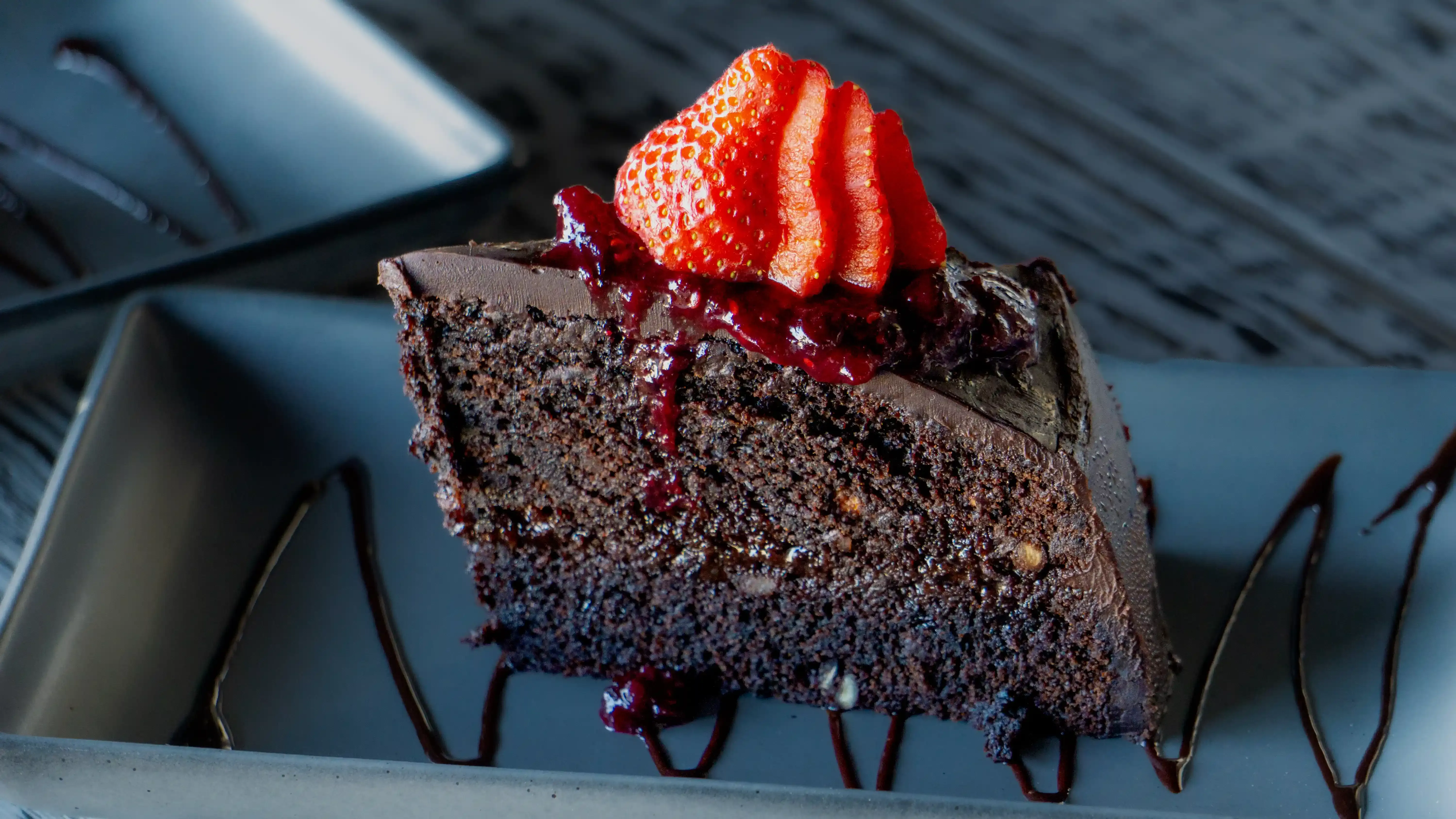 Pastel de chocolate con fresas y salsa de frutos rojos
