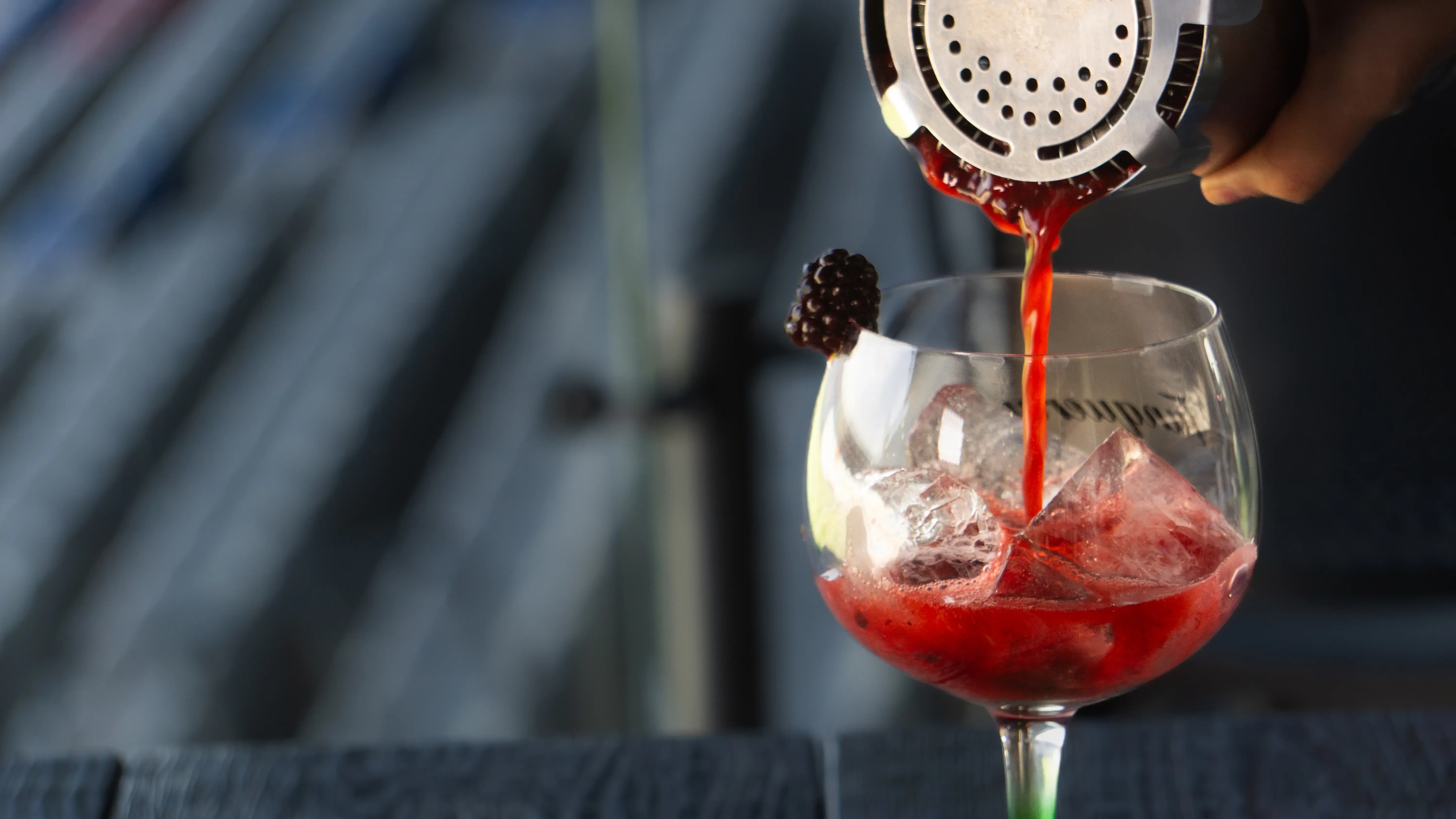 Cóctel de moras siendo servido en copa con hielo